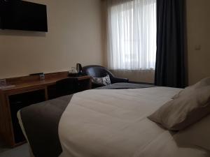 um quarto de hotel com uma cama, uma secretária e uma televisão em Hôtel Méribel em Bruxelas