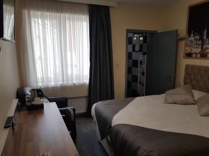 a hotel room with a bed and a desk and a window at Hôtel Méribel in Brussels