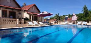 a large swimming pool with chairs and an umbrella at Hong Bin Bungalow in Phú Quốc