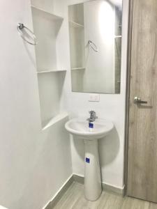 Baño blanco con lavabo y espejo en Caribbean Venture Apto 303 - Rodadero, Santa Marta, en Santa Marta