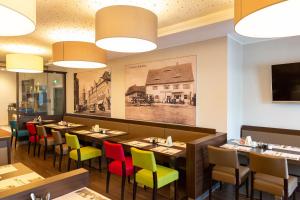 a dining room with long tables and colorful chairs at hotel bomonti Nürnberg West in Oberasbach