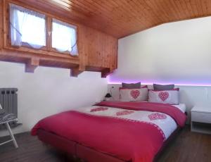 a bedroom with a bed with red and white sheets at Appartamenti LaDina Dolomiti in Padola