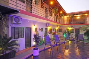 eine Terrasse mit Stühlen und einem Sonnenschirm auf einem Gebäude in der Unterkunft Pousada Recanto da Morada in Olímpia