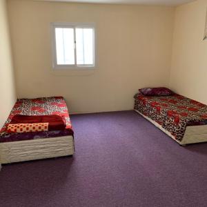 2 Betten in einem kleinen Zimmer mit Fenster in der Unterkunft Alkithri Apartments for Singls in Muhayil