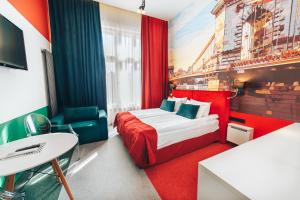 Habitación de hotel con cama roja y escritorio. en Cities Gallery Apart-hotel en Leópolis