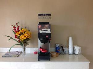 a coffee machine sitting on a counter with a vase of flowers at Deluxe Inn Airport in McAllen