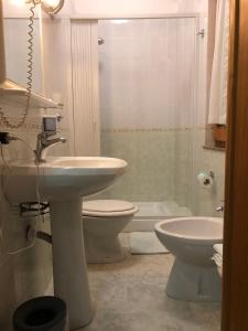 a bathroom with a sink and a toilet and a shower at Hotel Centrale in Quartu SantʼElena +21 photos