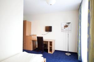 a room with a desk with a chair and a lamp at City-Hotel in Friesoythe