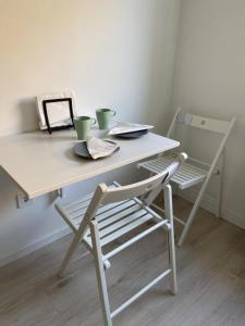 iHome Apartman 8.0 في بيتْش: طاولة بيضاء وكرسي عليه كوبين
