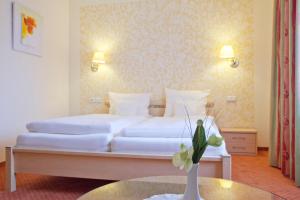 a bedroom with a bed and a table with a vase of flowers at City-Hotel in Friesoythe