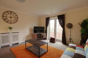 a living room with a tv and a clock on the wall at Sunnydale Serviced Apartments - Central location, with allocated parking in Wakefield