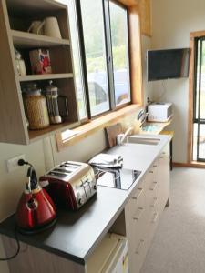 a kitchen with a sink, stove, and counter top at Kiwi Cabin and Homestay at Koru with hot tub in Barrytown