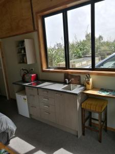 a kitchen with a sink and a window at Kiwi Cabin and Homestay at Koru with hot tub in Barrytown