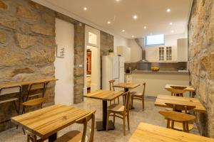 Un restaurante con mesas y sillas de madera y una cocina. en aDuquesa - GuestHouse, en Oporto