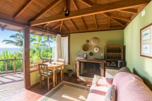 ein Wohnzimmer mit Kamin und Tisch in der Unterkunft Pousada Caminho do Rei in Praia do Rosa