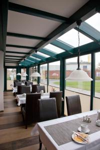 uma sala de jantar com mesas, cadeiras e janelas em City-Hotel em Friesoythe