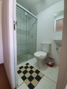 uma casa de banho com um WC e uma cabina de duche em vidro. em Garibaldi Hostel e Café em Curitiba
