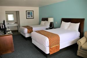 a hotel room with two beds and a television at Executive Inn & Suites Cuero in Cuero