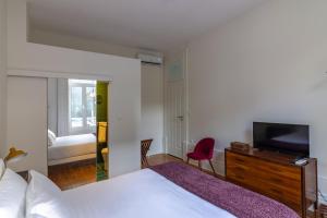 Un dormitorio con una cama blanca y un televisor. en aDuquesa - GuestHouse, en Oporto