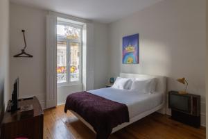 Un dormitorio con una cama y un televisor y una ventana. en aDuquesa - GuestHouse, en Oporto