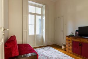 Una sala de estar con un sofá rojo y una ventana. en aDuquesa - GuestHouse, en Oporto