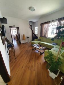 a living room with a green couch and wooden floors at Garibaldi Hostel e Café in Curitiba