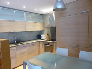 a kitchen with wooden cabinets and a glass table at Gaztanbide Apartamento rural in Ochagavía