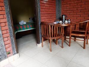 une table et des chaises en bois à côté d'un mur en briques rouges dans l'établissement Patra House, à Ubud