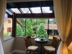 a room with a large window with a table and chairs at Residencial Jardim dos Pinheiros 279 in Canela
