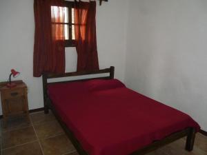 a bedroom with a red bed and a window at PORTOFINO BARRIO COUNTRY in Piriápolis