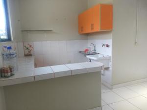 una cocina blanca con armarios naranjas y fregadero en Departamento Melly, en Tarapoto