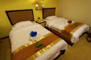 龍運的住宿－SIX VILLA INN，两张位于酒店客房的床,上面有鲜花