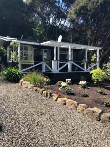 a small white house with a garden in front of it at Hideaway - A Couples Retreat in Akaroa