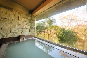 a swimming pool in a room with a large window at Centurion Hakone Bettei in Hakone