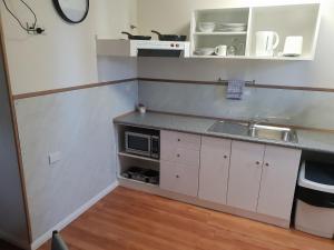 a small kitchen with a sink and a microwave at Big4 Acclaim Prospector Holiday Park in Kalgoorlie