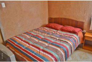 a bed with two red pillows in a bedroom at La Casa Blanca in San Pedro de Atacama
