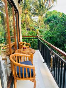 balcone con tavolo, sedie e alberi di Sari House Ubud ad Ubud