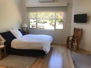 
a bedroom with a bed, chair and a window at SIGNAL BOX Short Stay in Gembrook
