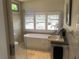 
a bathroom with a tub, sink, and toilet at SIGNAL BOX Short Stay in Gembrook
