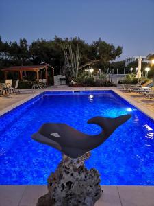een dolfijnsculptuur in een zwembad 's nachts bij Louis Luxury Villa by filoxenia in blue in Rhodos-stad