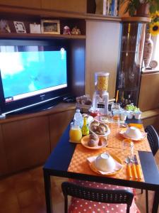 a table with food and a television in a room at Orange House in Varenna