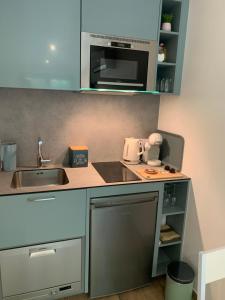 a small kitchen with a sink and a microwave at "Une Pause au Vert" Studio 2 personnes in Châteauvieux