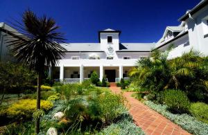 a large white building with a palm tree in front of it at Collection Luxury Apartments - Rozenhof Villa in Stellenbosch