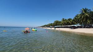 邦賢的住宿－The Patio Bangsaen，水中的人与船的海滩