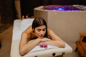 a woman laying in a bath tub with a flower at Garni Hotel Zen in Niš