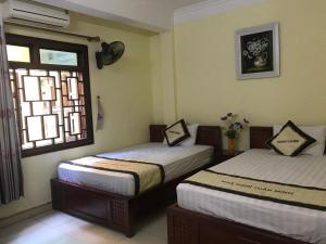 two beds in a room with a window at Tuan Minh Guest House in Diện Biên Phủ