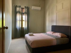a bedroom with a bed with pink pillows and a window at Sarah Guesthouse in Kuala Terengganu