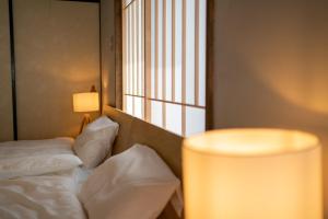 a room with a bed with a lamp and a window at ゑびすや in Kofu