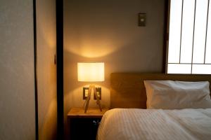 a bedroom with a bed and a lamp on a table at ゑびすや in Kofu +24 photos
