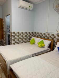 1 dormitorio con 2 camas y almohadas verdes en Thảo Trân, en Hà Tiên